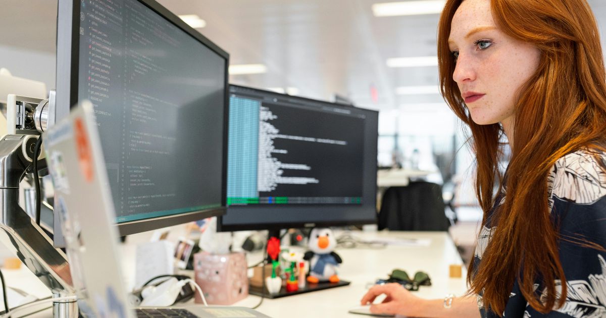 Woman coding on two screens